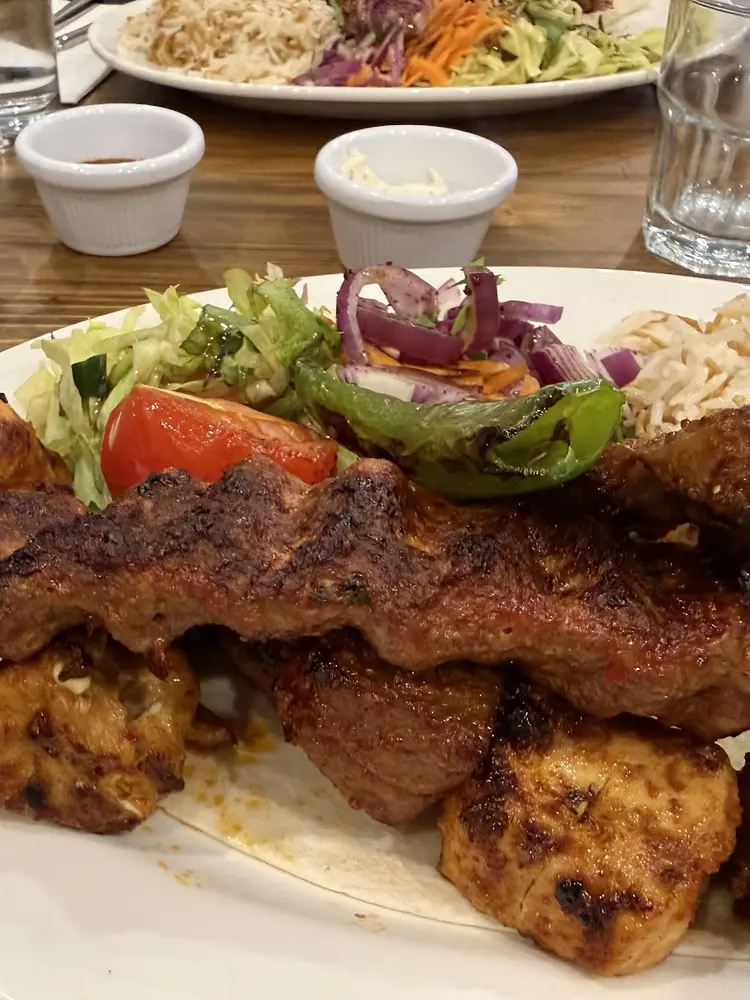 Grilled lamb and chicken skewers served over flatbread with rice and salad