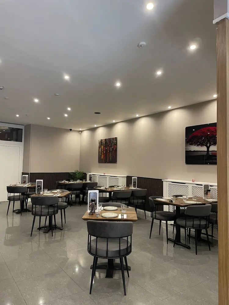 Modern dining room with wooden tables, grey velvet chairs and framed artwork